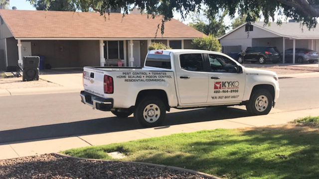 A KY-KO Pest Prevention truck sits parked on the street outside this Phoenix-area home.